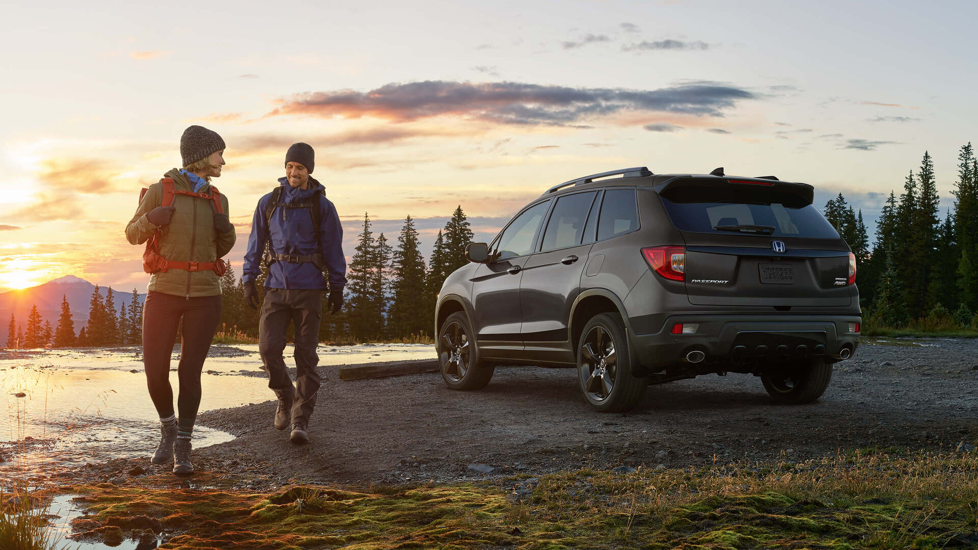 A couple going for a hike in the forest next to their green 2022 Honda SUV