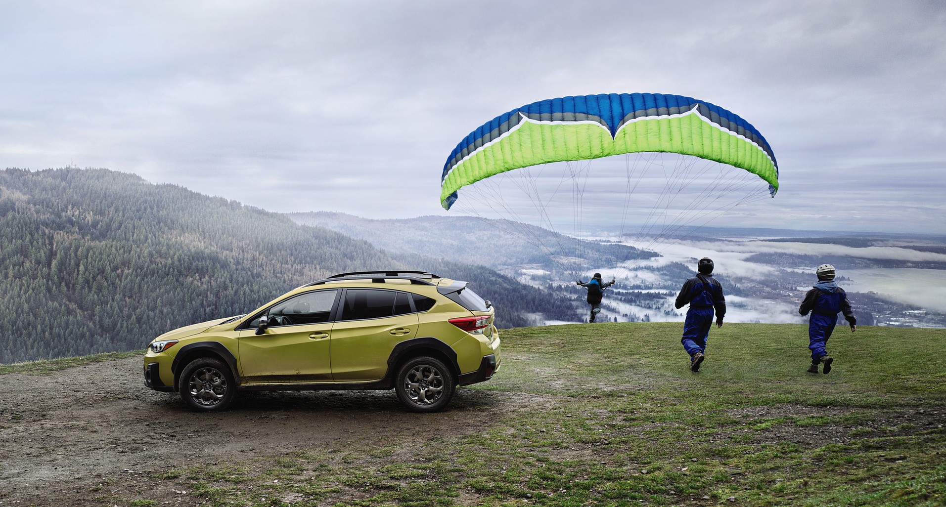 vus subaru vert 2021-2022 sur le haut d'une montagne avec des personnes en parapente